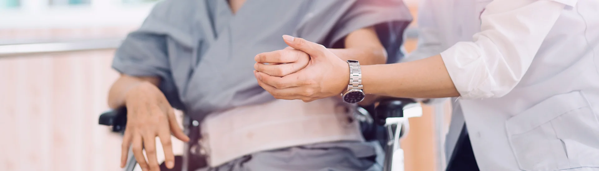 a close up of nurses hands helping a patient in a wheelchair