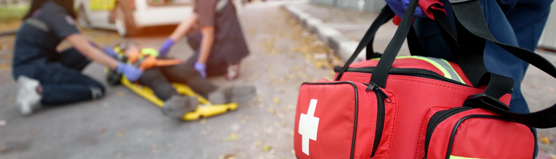 close up of two paramedics attending to a patient carrying a supply bag
