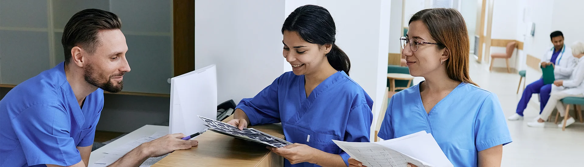 a male nurse and two female nurses talking at the nurses desk